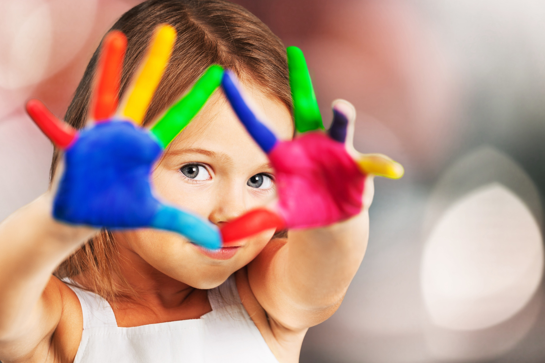 child with multiple paint colours on hands