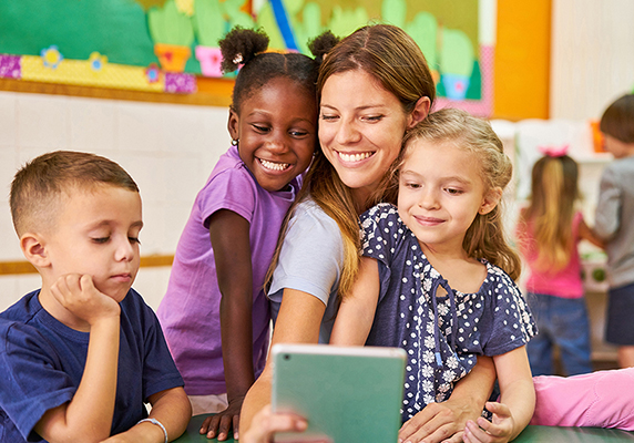 woman and three kids in a classroom learning environment